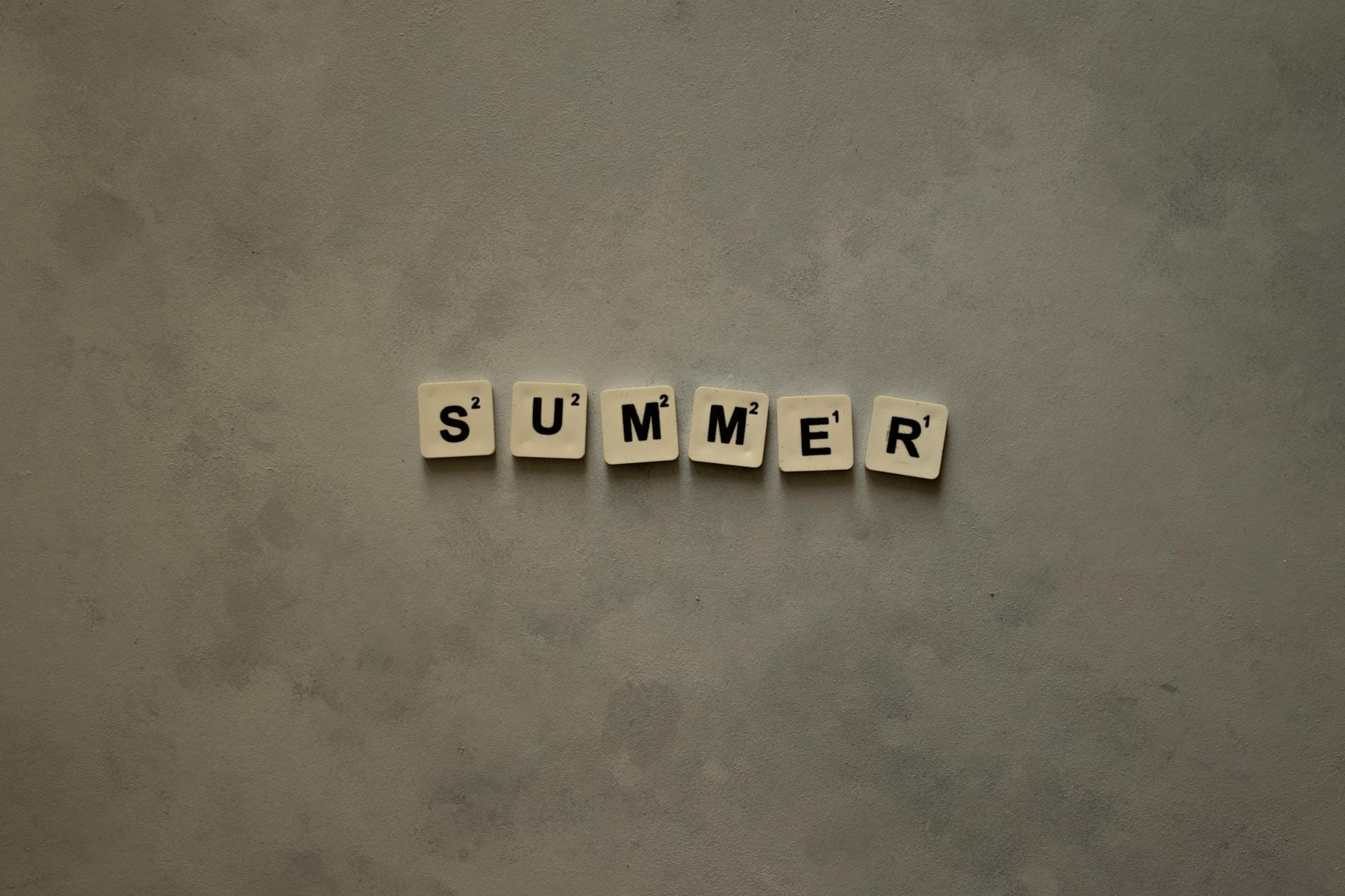 Kafelki scrabble układające się w słowo Summer na szarej fakturze