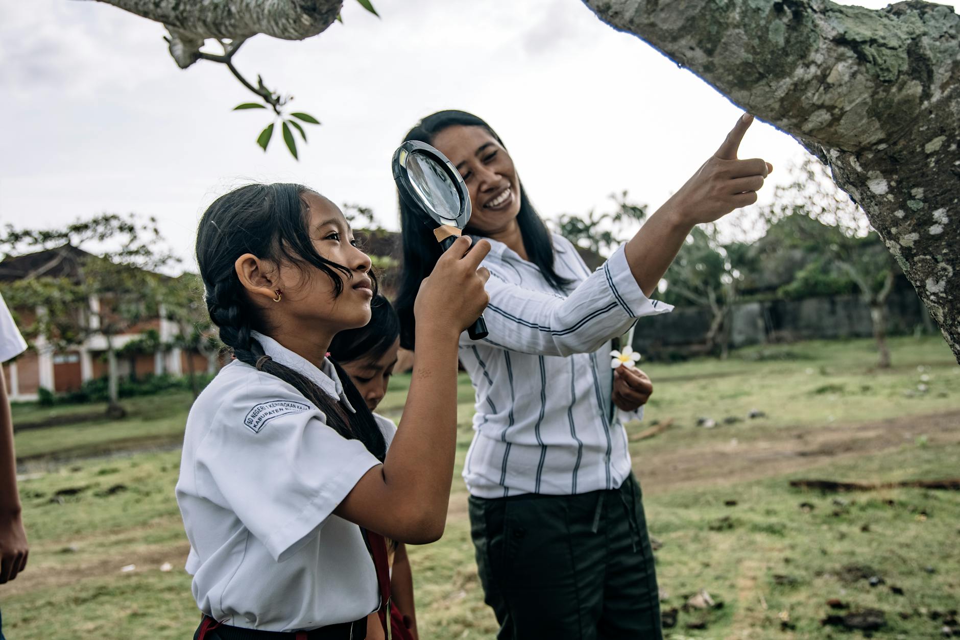 Edukacja w terenie: 12 pomysłów na lekcje poza klasą Nauczyciel i uczniowie w mundurkach badają przyrodę lupą na dworze