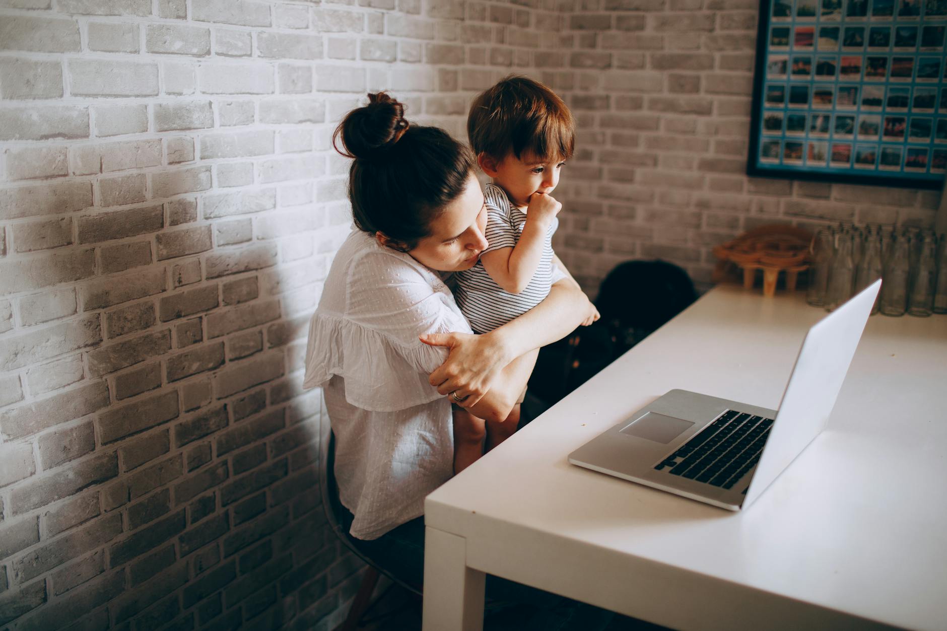 Mama z dzieckiem rozmawiają przez wideorozmowę na laptopie w domu