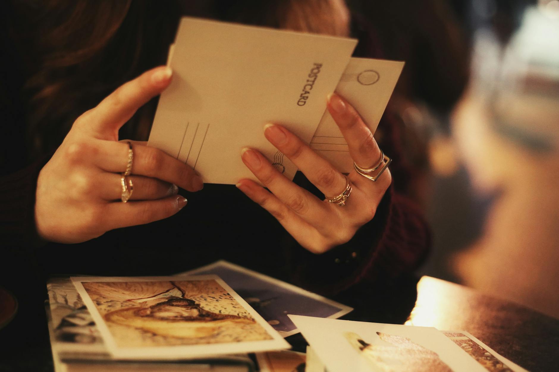 Kobieta trzyma pocztówki w przytulnej kawiarni