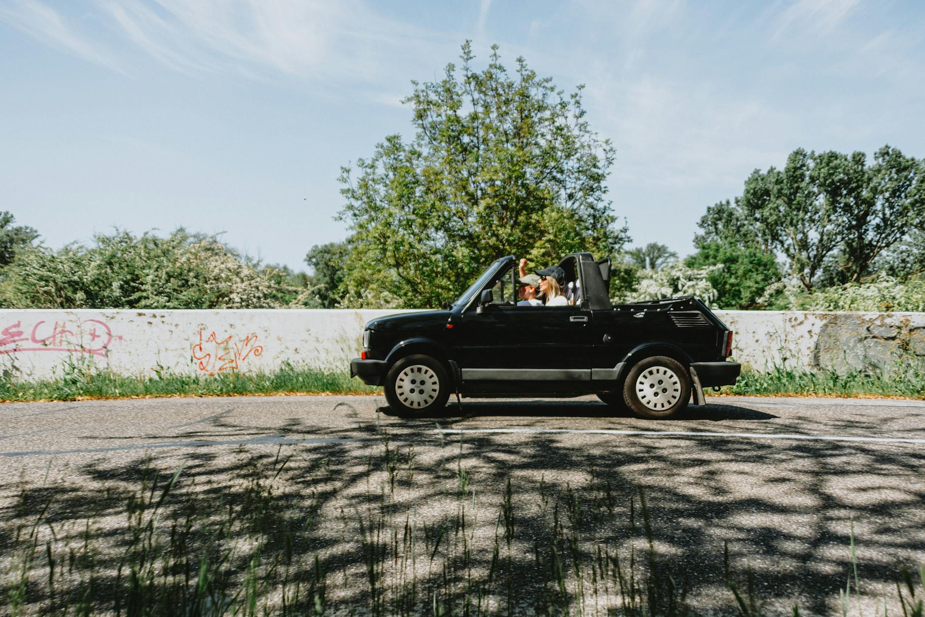 Para w czarnym kabriolecie jedzie malowniczą trasą w słoneczny dzień