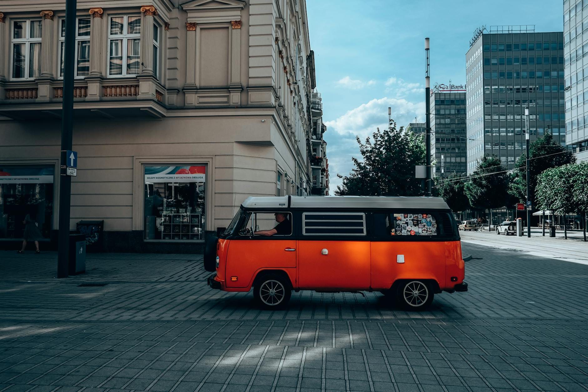 Pomarańczowy zabytkowy bus Volkswagen na słonecznej ulicy w Poznaniu