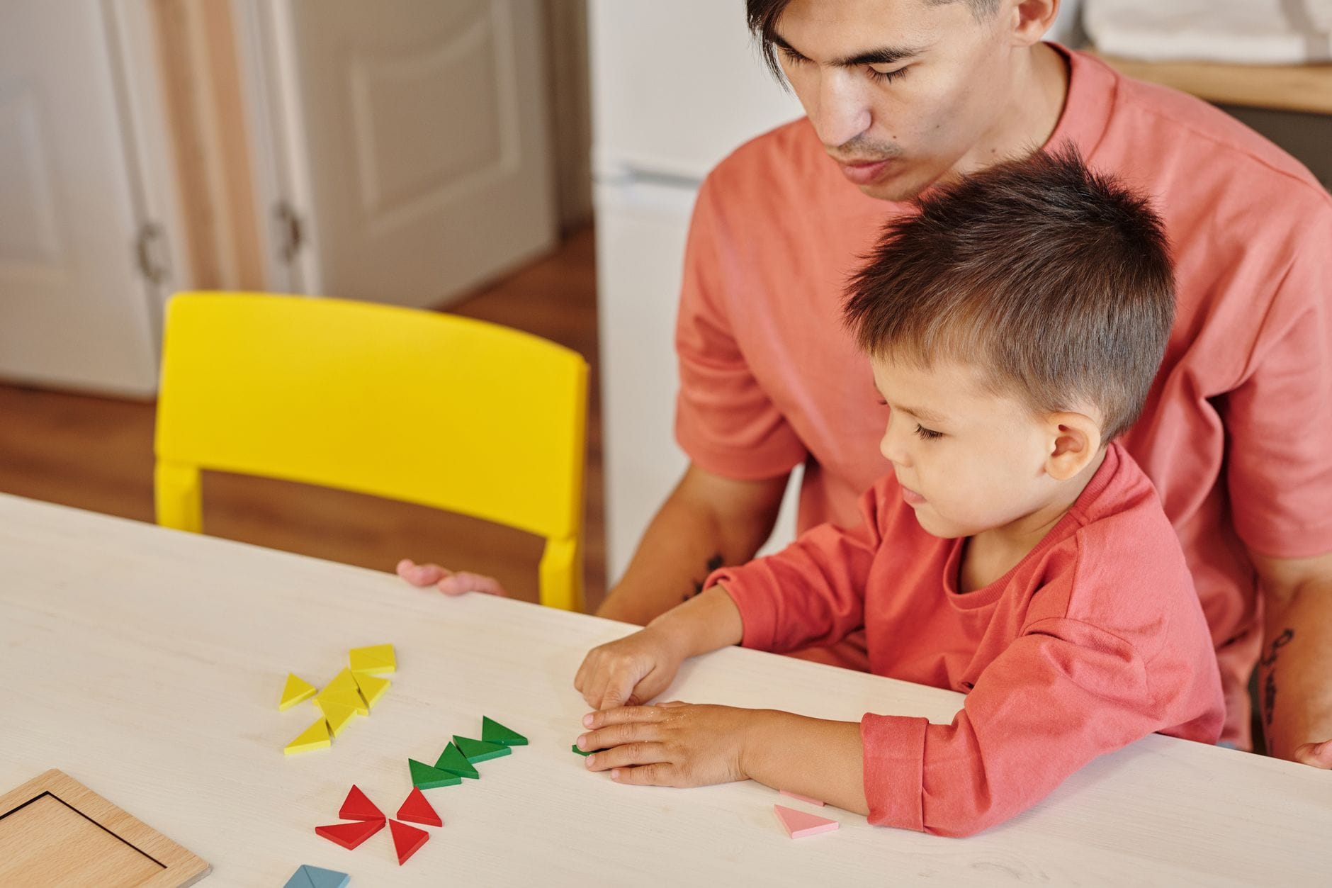 Ojciec i syn układają kolorowe kształty edukacyjne w domu