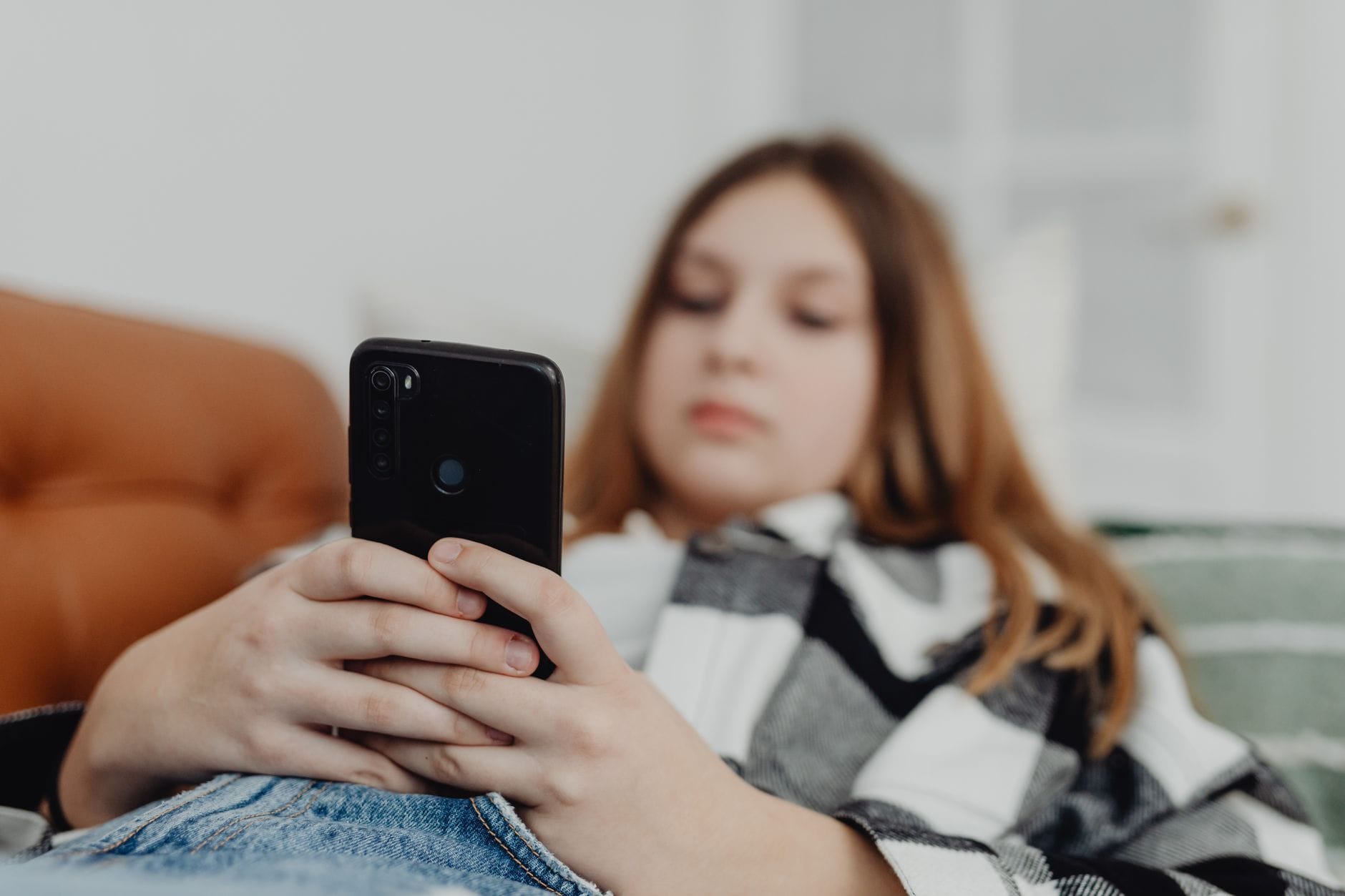 Oszustwa na BLIK u nastolatków: jak działają i jak ich uniknąć Nastolatka korzysta ze smartfona, odpoczywając na kanapie